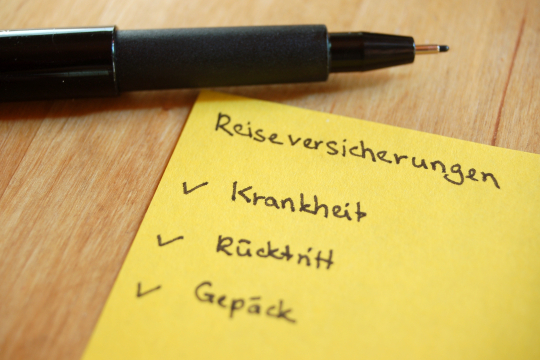 Schwarzer Stift liegt über gelben Zettel mit dem Vermerkt Reiseschutz